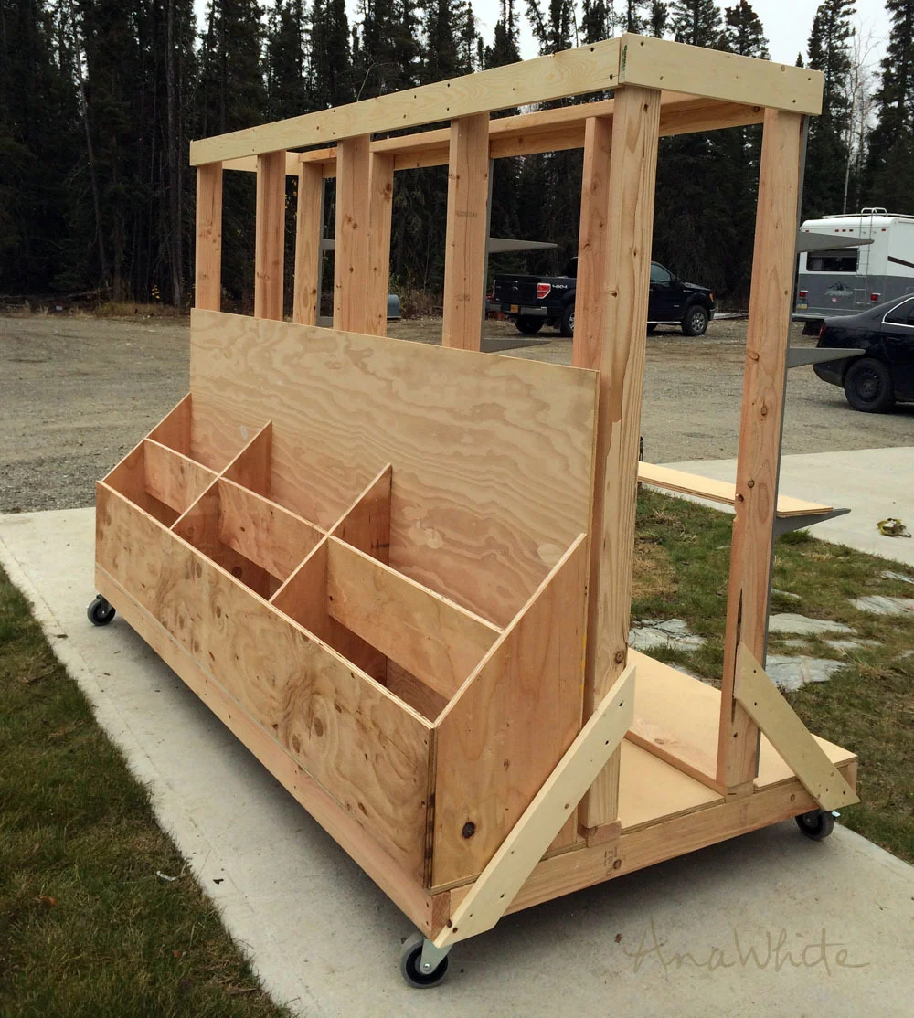 Large DIY rolling lumber cart built from plywood and 2x lumber with vertical storage bays for sheet goods, plywood offcuts, and long boards.