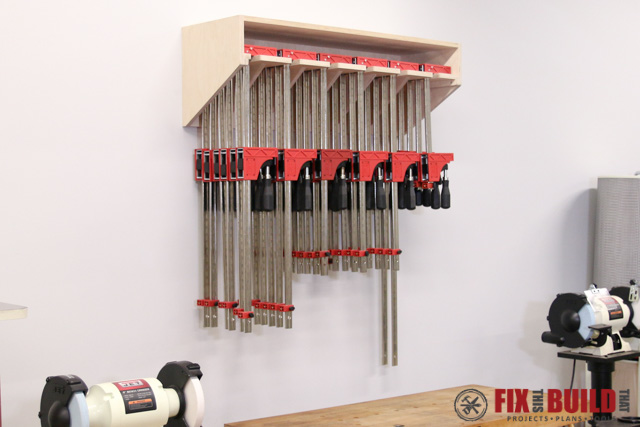 Large wall-mounted clamp rack with individual storage slots for organizing parallel clamps.