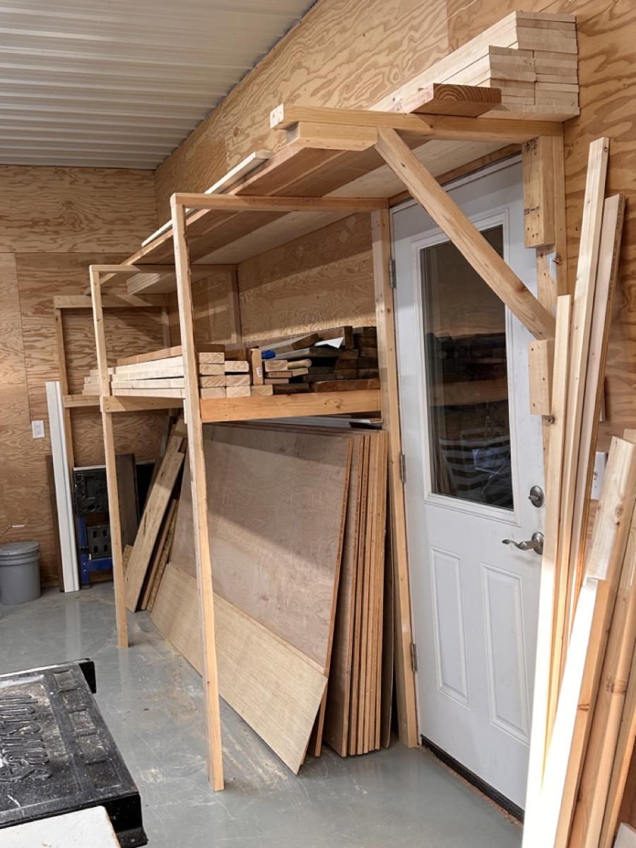 DIY floor-to-ceiling lumber storage rack built holding boards and sheet goods.