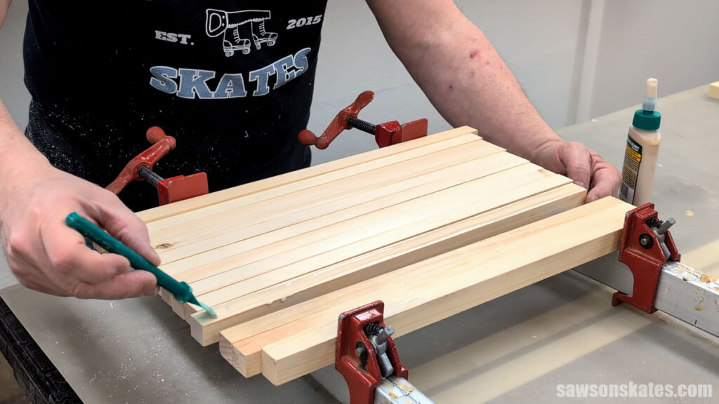 Person applying wood glue to several boards before clamping them together.