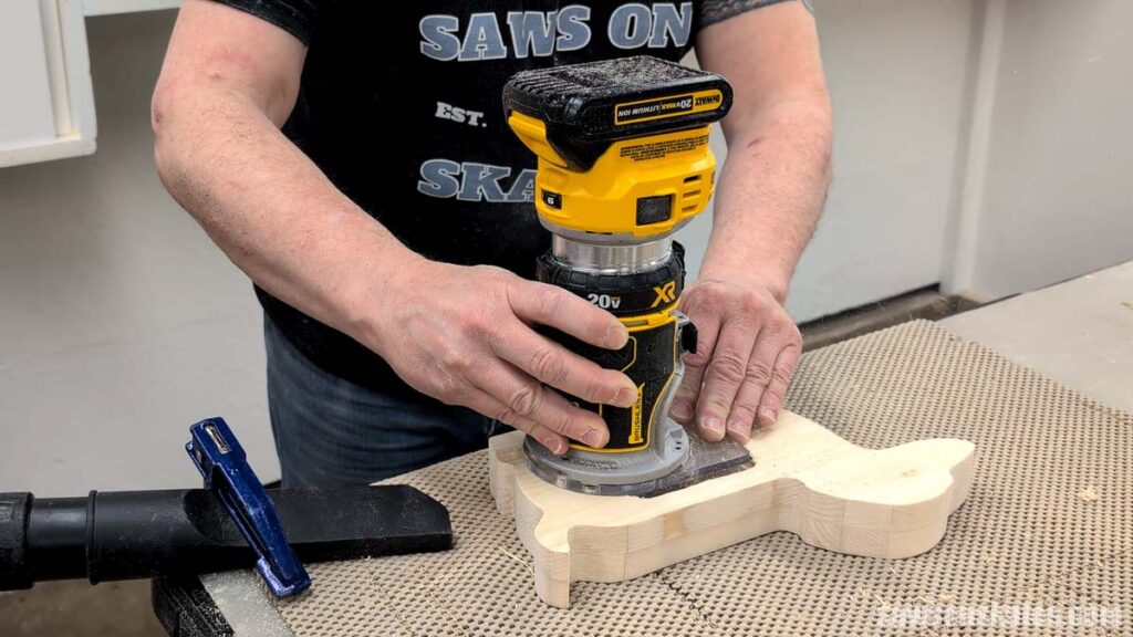 Person using a router to cut a recessed area in a wooden dog shape.