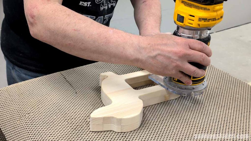 Person using a router to roundover the outside edges of a dog-shaped picture frame.