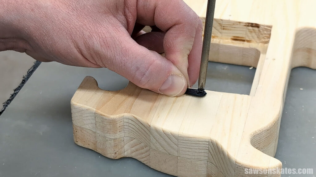 Person using a screwdriver to attach a turn button to the back of a picture frame.