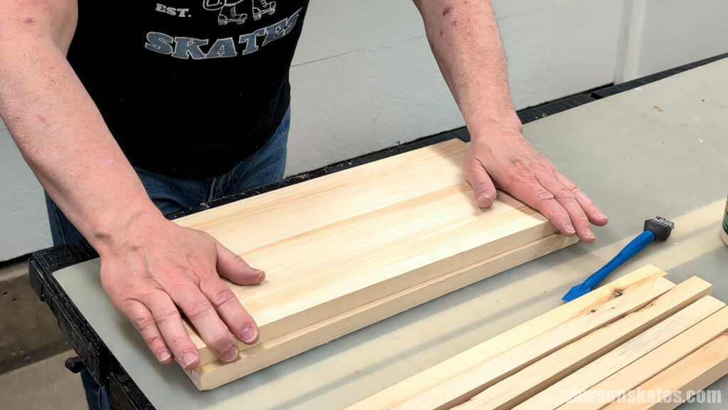 Person pressing two glued-up wood panels together.
