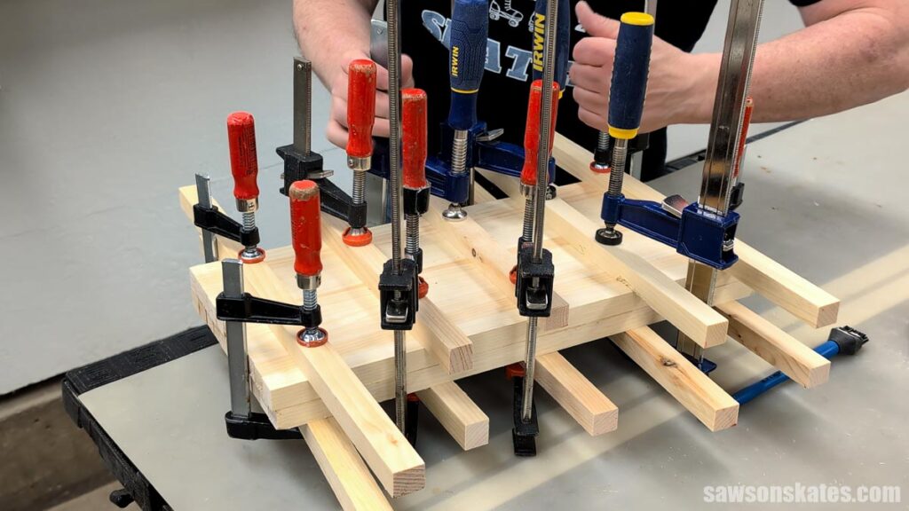 Wood panel glue-up secured with several clamps while the glue dries.