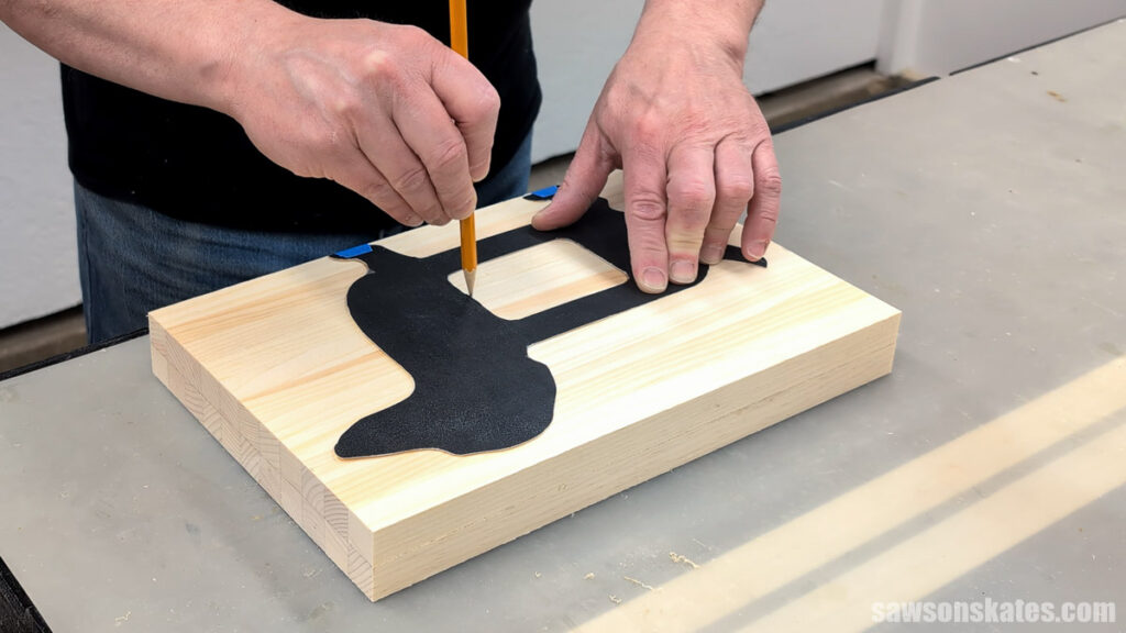 Person tracing a dog template onto a board with a pencil.