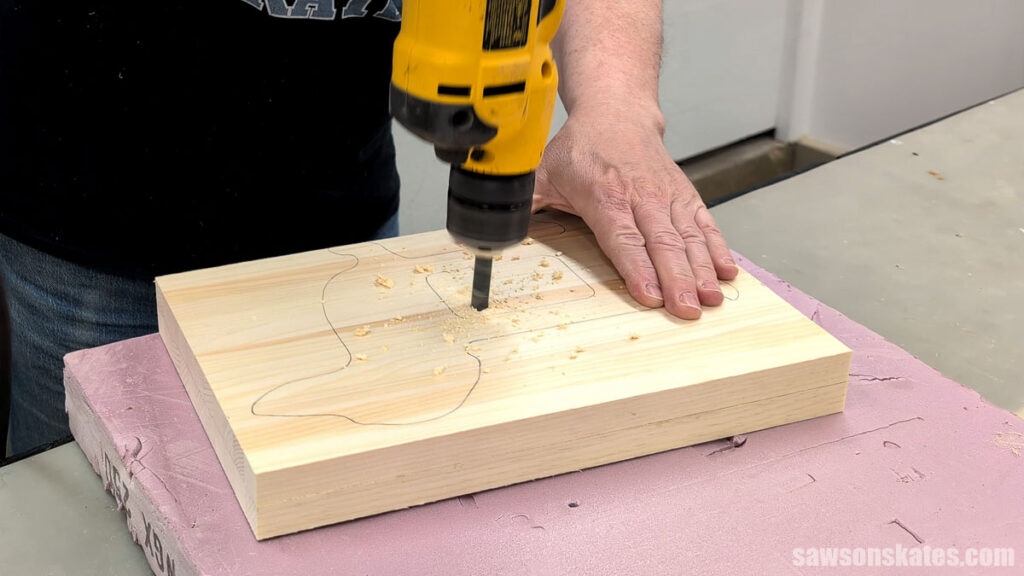 Person using a drill to make a hole in a board.