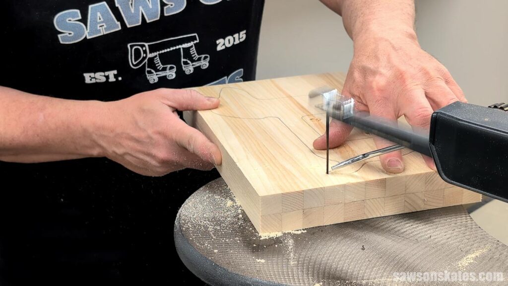Person using a scroll saw to cut a shape out of a board.