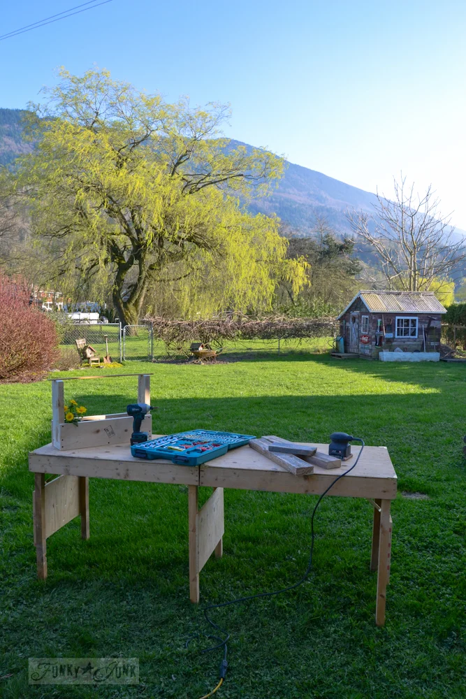 Folding workbench with tools in a yard and trees in the distance