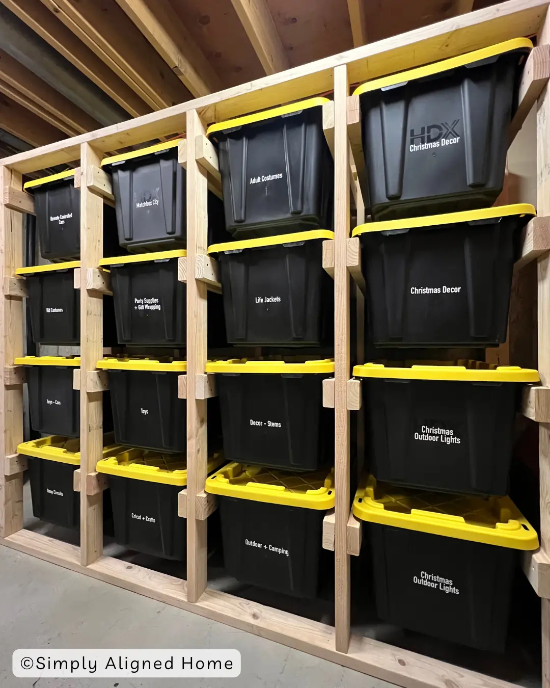 Wooden garage storage rack holding labeled plastic totes with yellow lids.