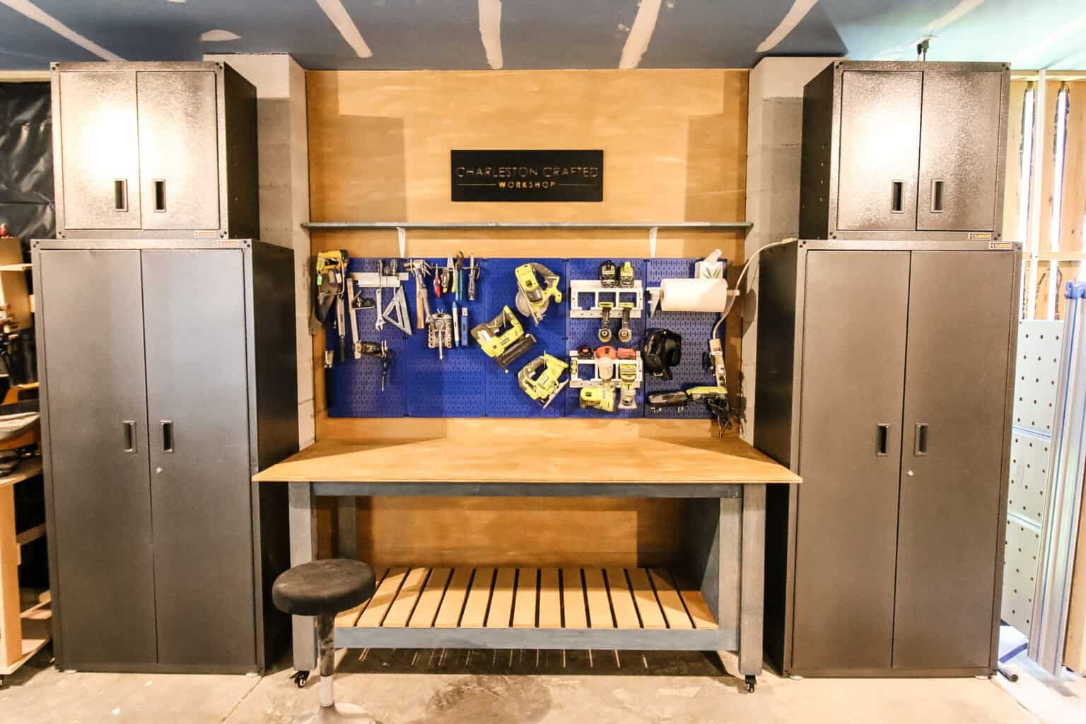 Mobile workbench with a large top and slatted shelf between two cabinets in a workshop