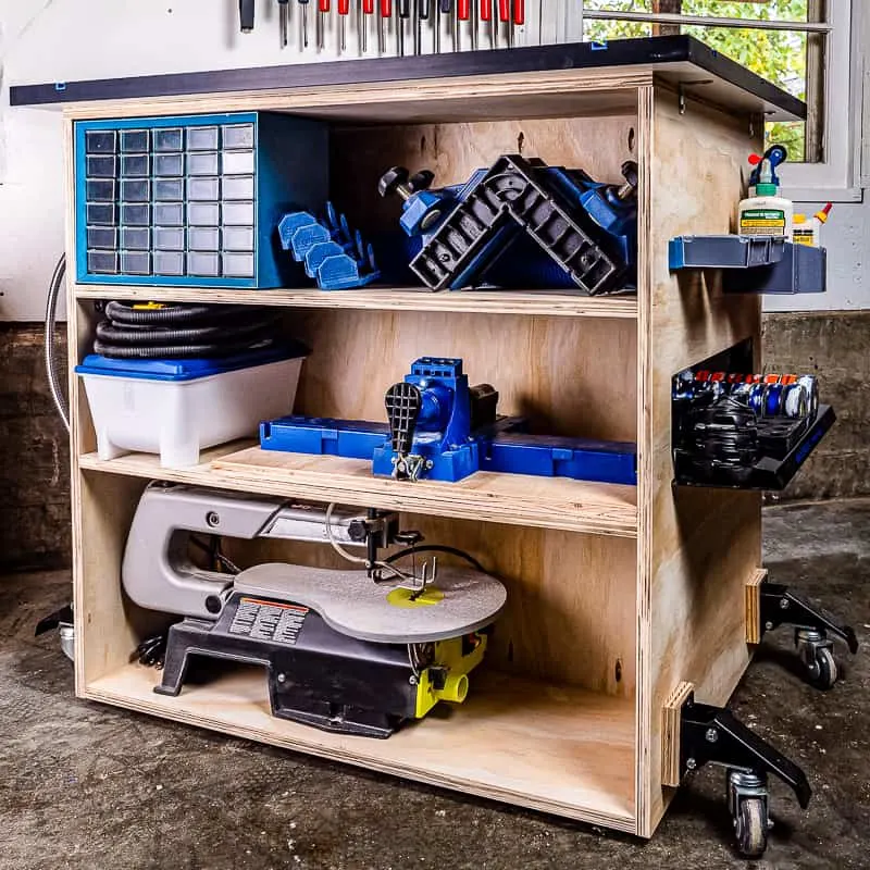 Small rolling workbench with three interior storage shelves and more storage on the outside