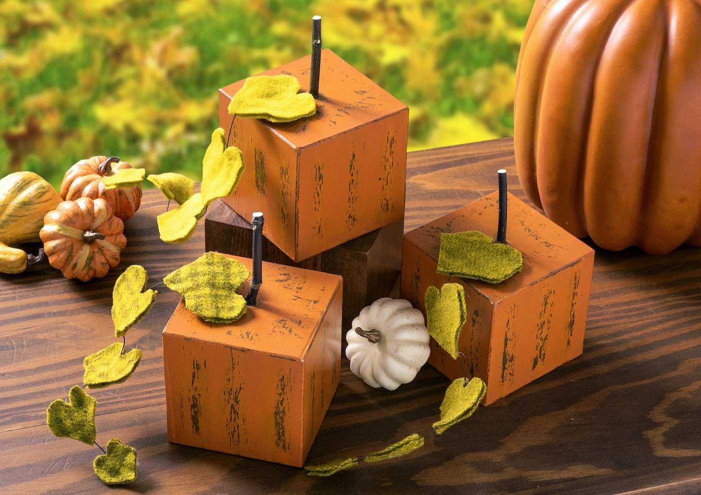 Square wood blocks painted to look like pumpkins with twigs for stems