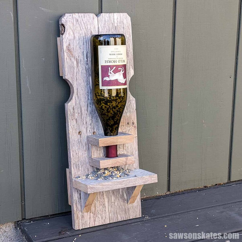 Wooden bird feeder made from reclaimed fence pickets and a wine bottle