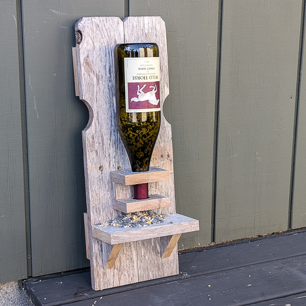 Wooden bird feeder made from reclaimed fence pickets and a wine bottle