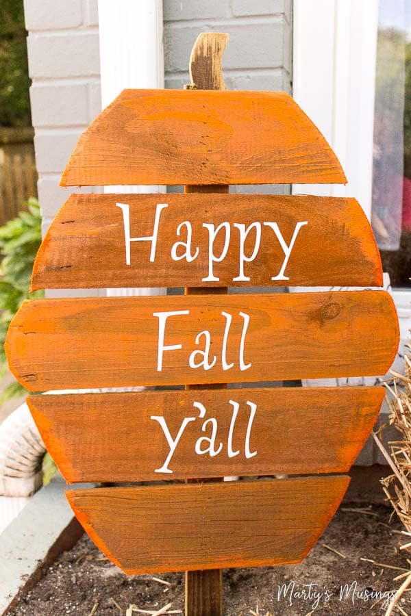 Planks stacked vertically, cut in the shape of a pumpkin with words, "Happy Fall Y'all"
