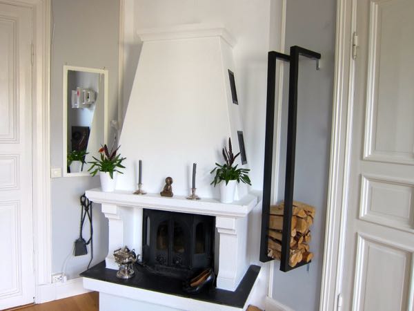 Black-painted firewood rack on a wall next to a fireplace