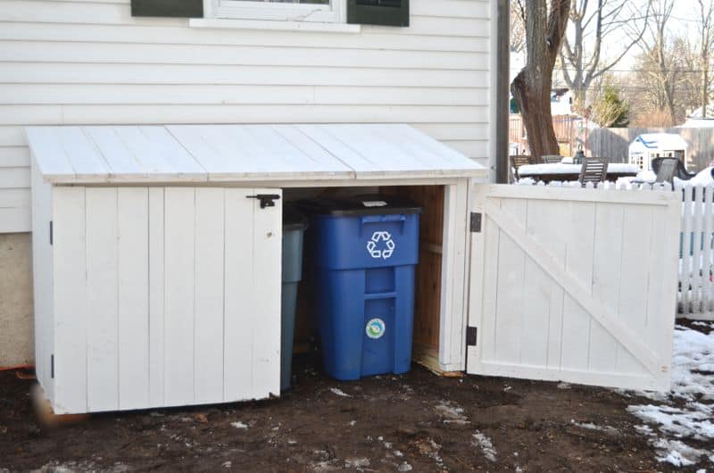 White painted enclosure with two doors to store garbage cans