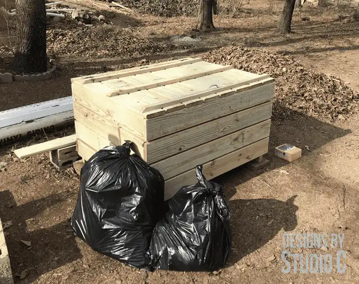 Wood enclosure to store garbage with two garbage bags next to it
