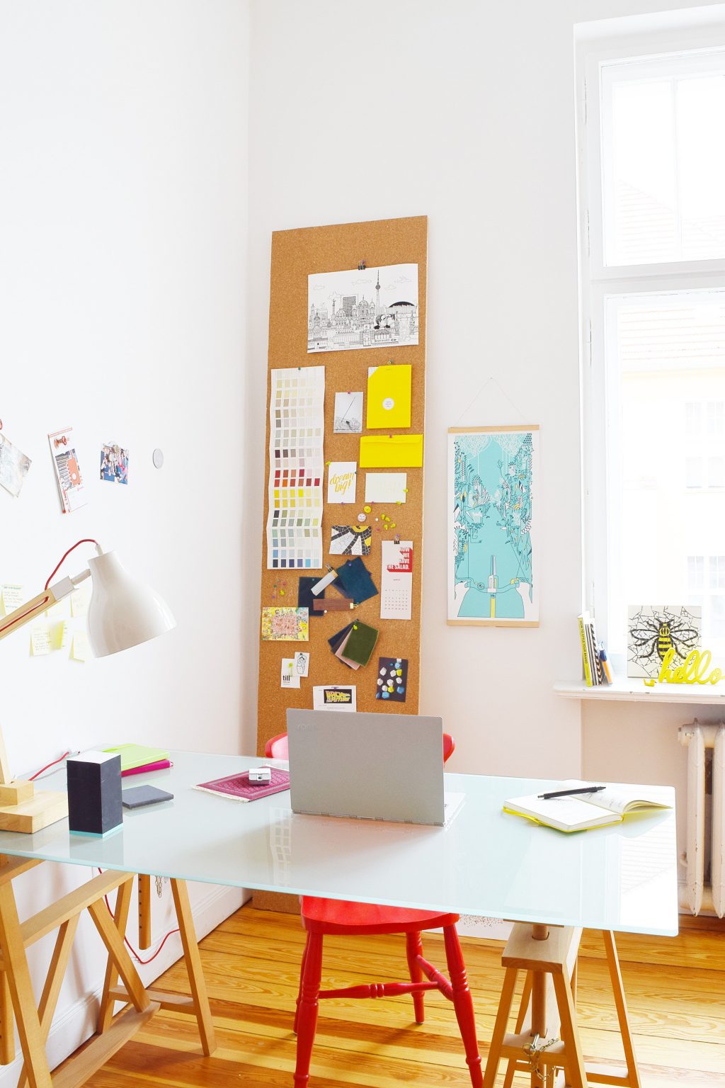 Tall corkboard leaning in the corner of a room behind a desk