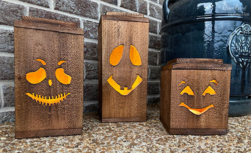 Three wood Halloween lanterns on a deck