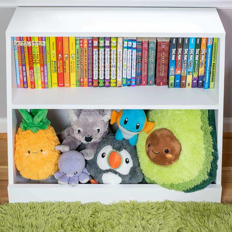 White bookcase with books on the top shelf and stuffed animals on the lower one