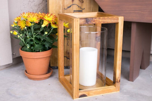 Stained wood lantern next to a potted mum