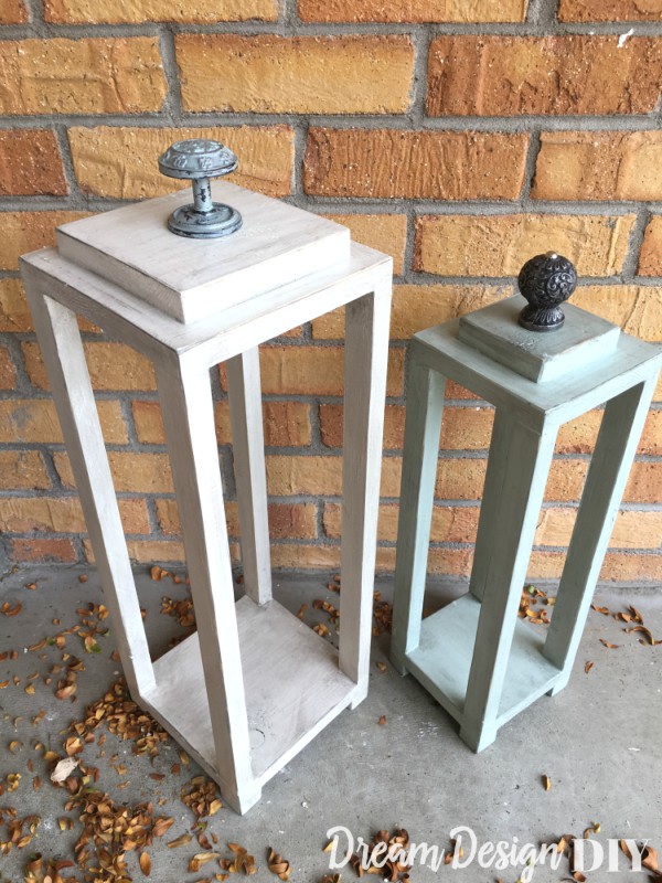 Two wood lanterns with knob handles on a porch