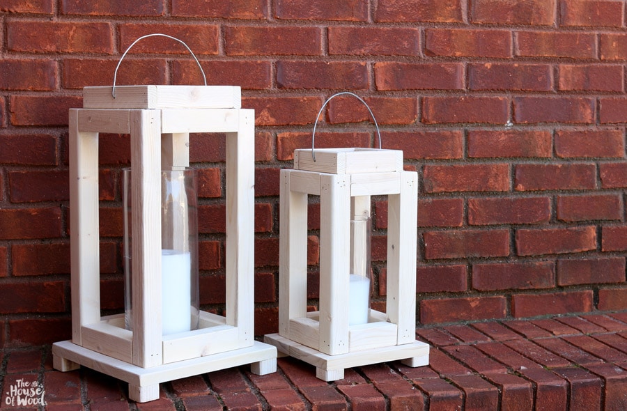 White painted wood lanterns in front of a brick wall