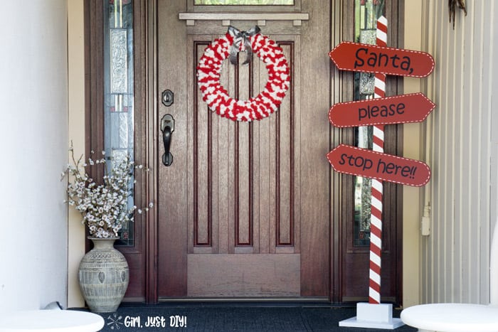 DIY outdoor Christmas sign next to a front door that says Santa, Please Stop Here!