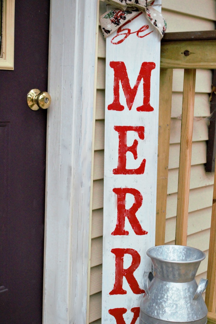 DIY outdoor Christmas sign next to a front door that says Be Merry
