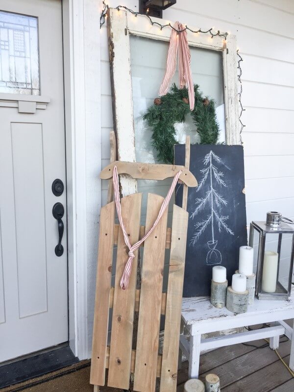 DIY Christmas sled on a porch leaning near a door