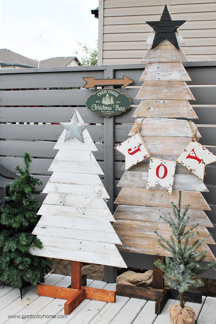 A pair of DIY outdoor wood Christmas trees next to a fence