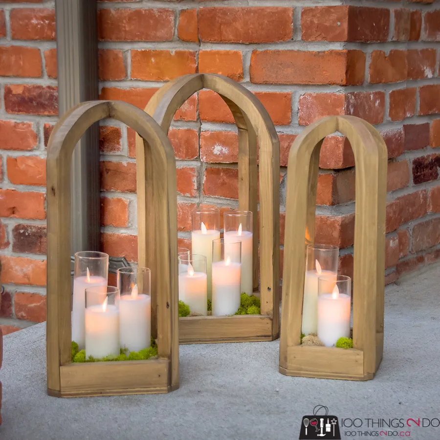 Three round-top wood lanterns on a porch next to a brick wall