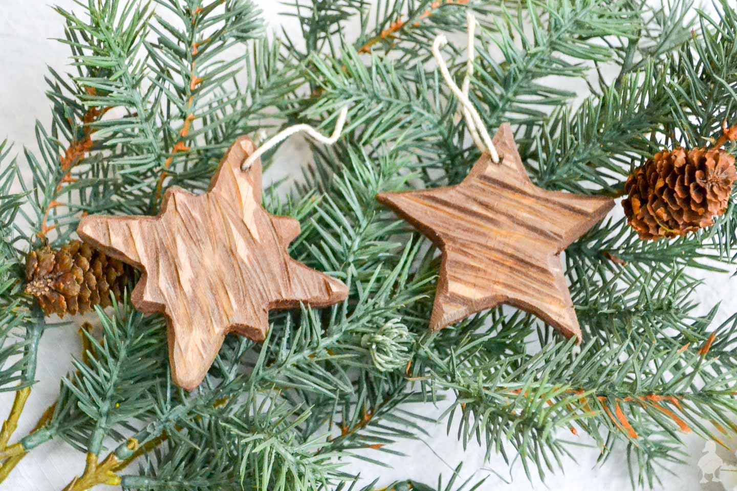 Rustic carved wooden Christmas ornaments on an evergreen