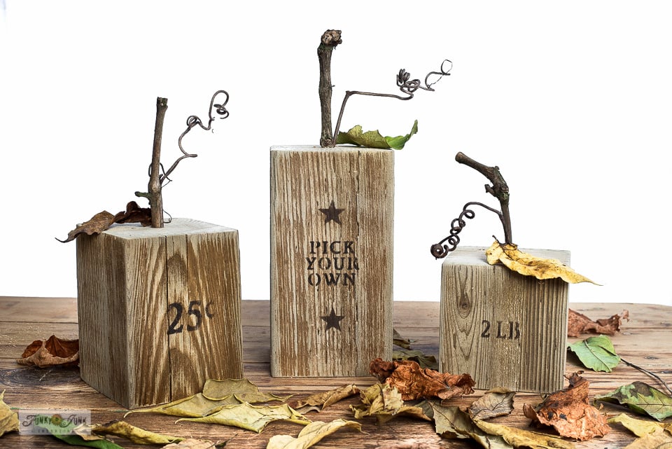 Wood blocks in a rustic stain made to look like pumpkins with stencils and twigs for stems