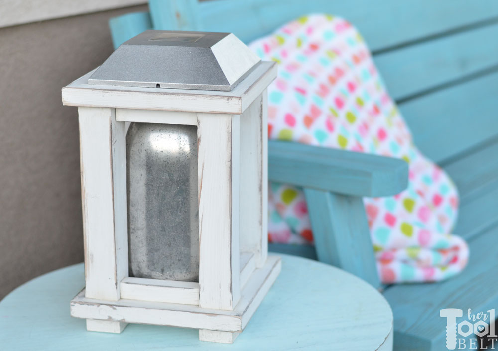 White painted lantern on a table next to an outdoor couch