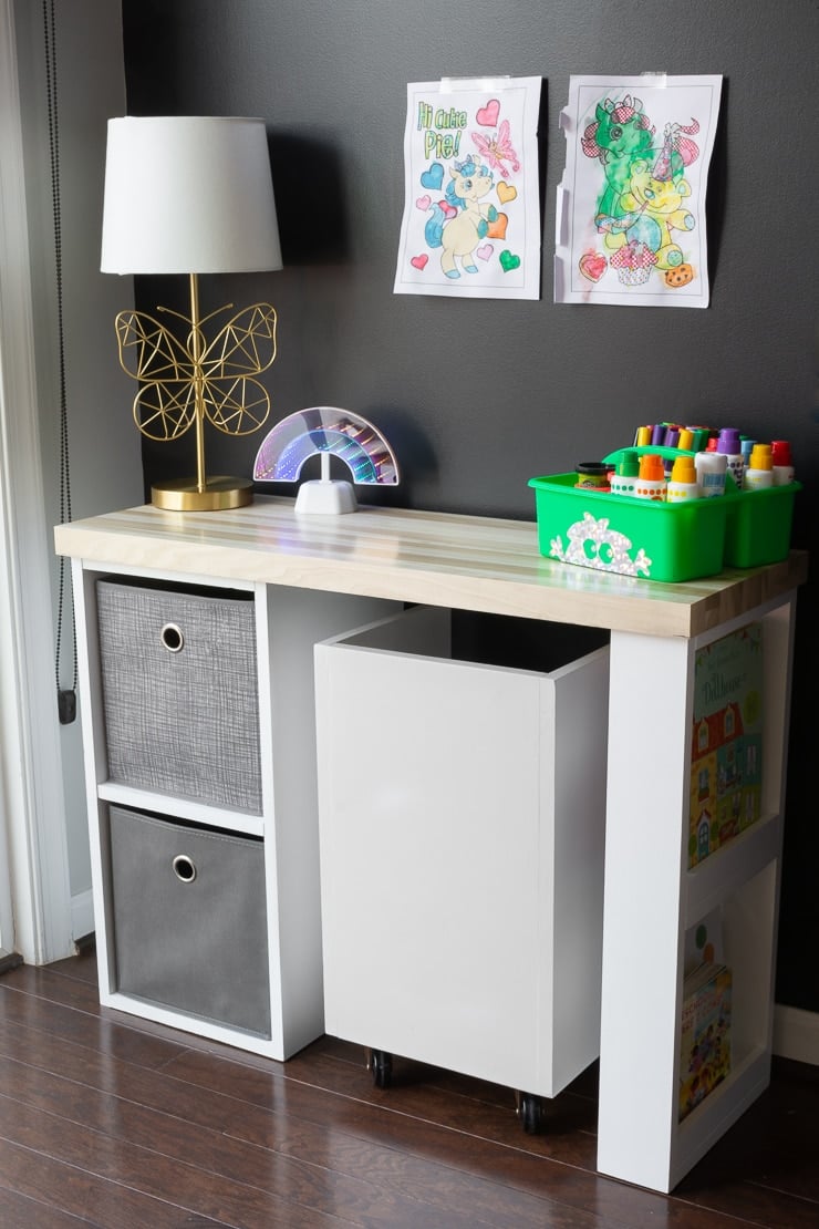 Small handmade desk for kids with two fabric bins on the left and storage on the right