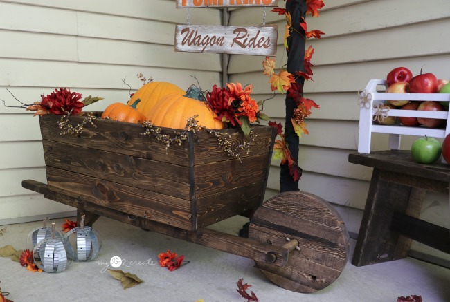 Dark stained wood wheelbarrow filled with pumpkins on a porch