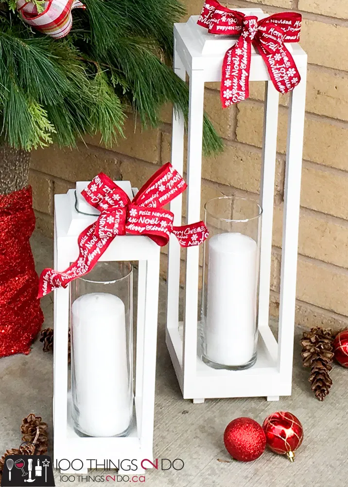 Two white painted lanterns with red Christmas bows