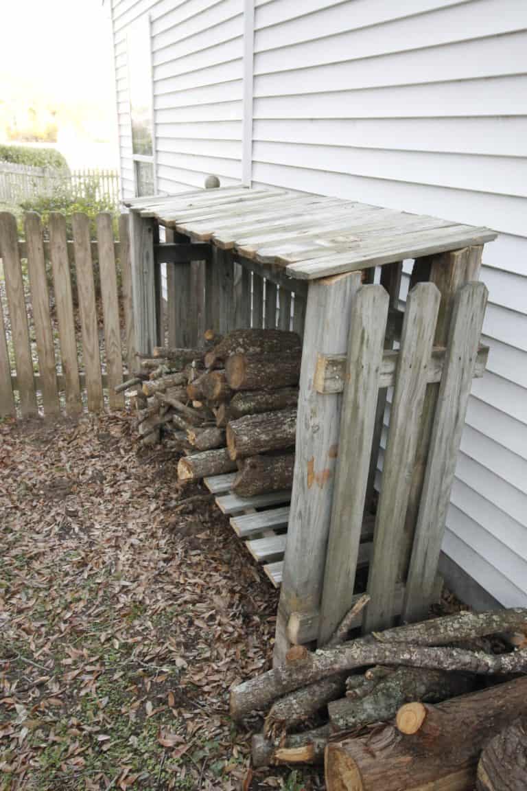 Firewood shed made from a recycled fence next to a house