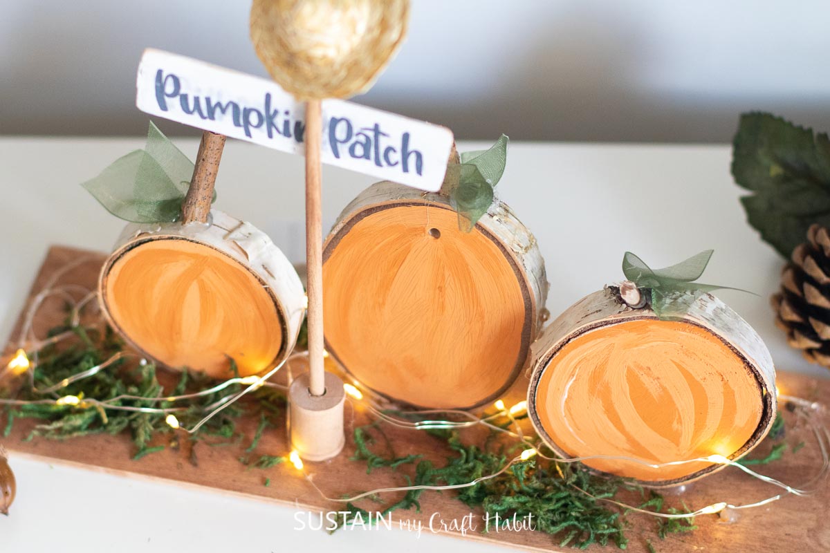 Wood slices painted to look like pumpkins with a little sign that says pumpkin patch