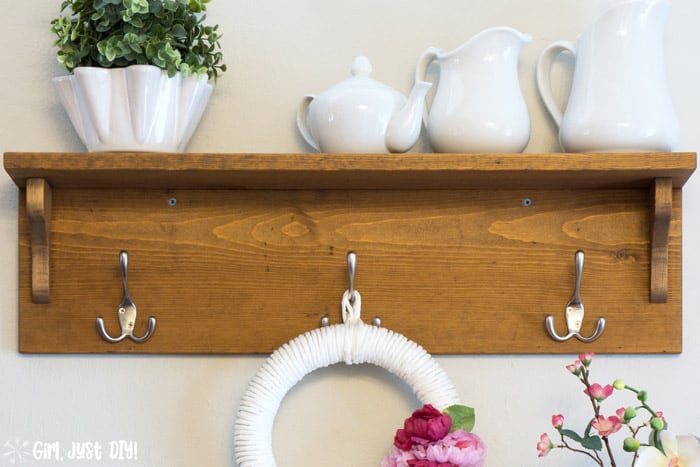 Wooden coat rack with three hooks and a shelf above