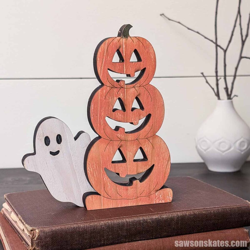Wooden stacked jack-o-lanterns with a ghost sitting on books
