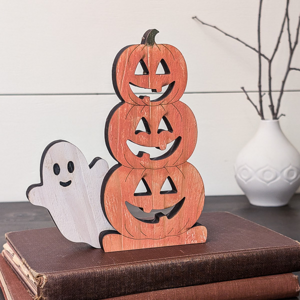 Wooden stacked jack-o-lanterns with a ghost sitting on books