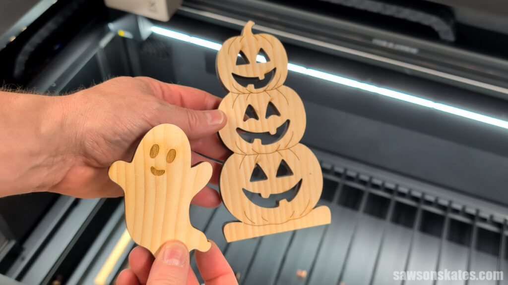 Hand holding the laser cut ghost and pumpkins