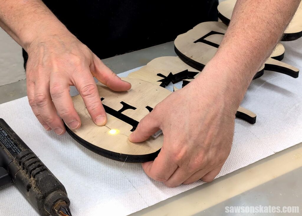 Hot gluing twinkle lights to the back of the fall pumpkin sign