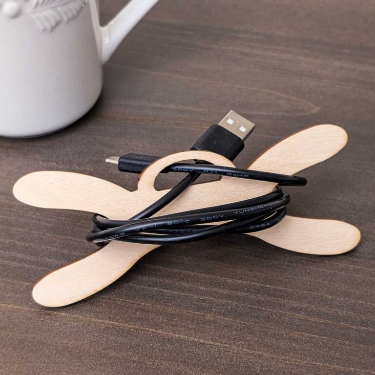 Wooden cord organizer with a black charging cable on a tabletop.