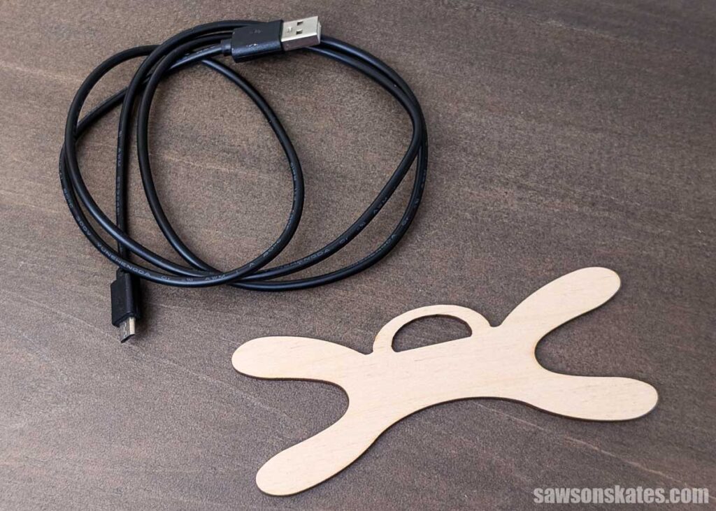 Black charging cable next to a wooden cord organizer on a table