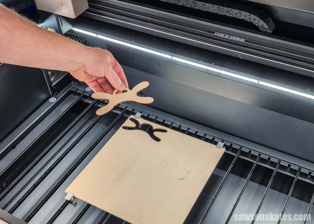 Scott removing a wood cord organizer from the bed of a laser cutter